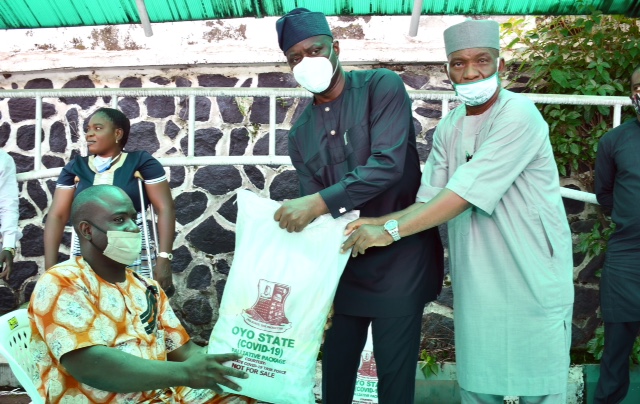 Oyo State Governor, Engr Seyi Makinde (middle); being assisted by Commissioner for Special Duties, Chief Bayo Lawal (right) presenting palliative material to Mr Oyayinka Babawale during the symbolic distribution of Palliatives to People living with disabilities held at Governor's Office, Ibadan. PHOTO: Oyo State Government.